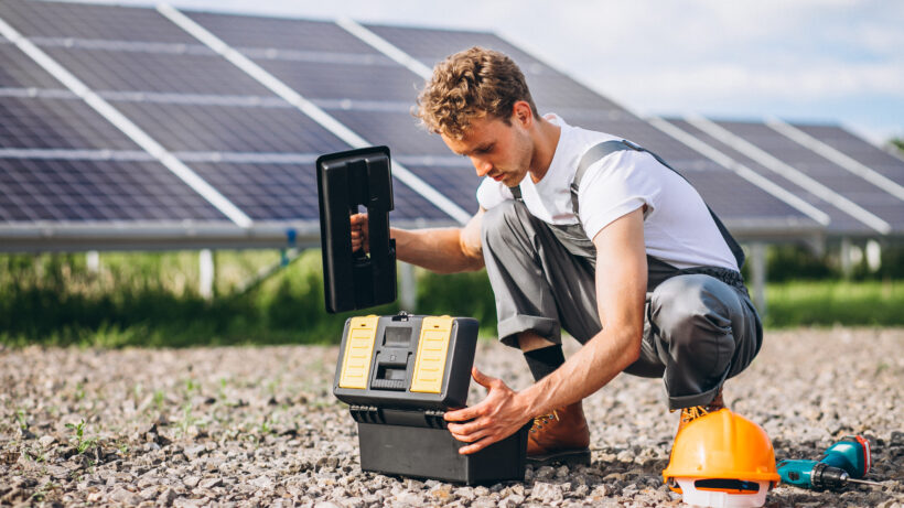 Solar technician inspecting equipment near solar panels, highlighting net metering setup by solar companies in Kochi