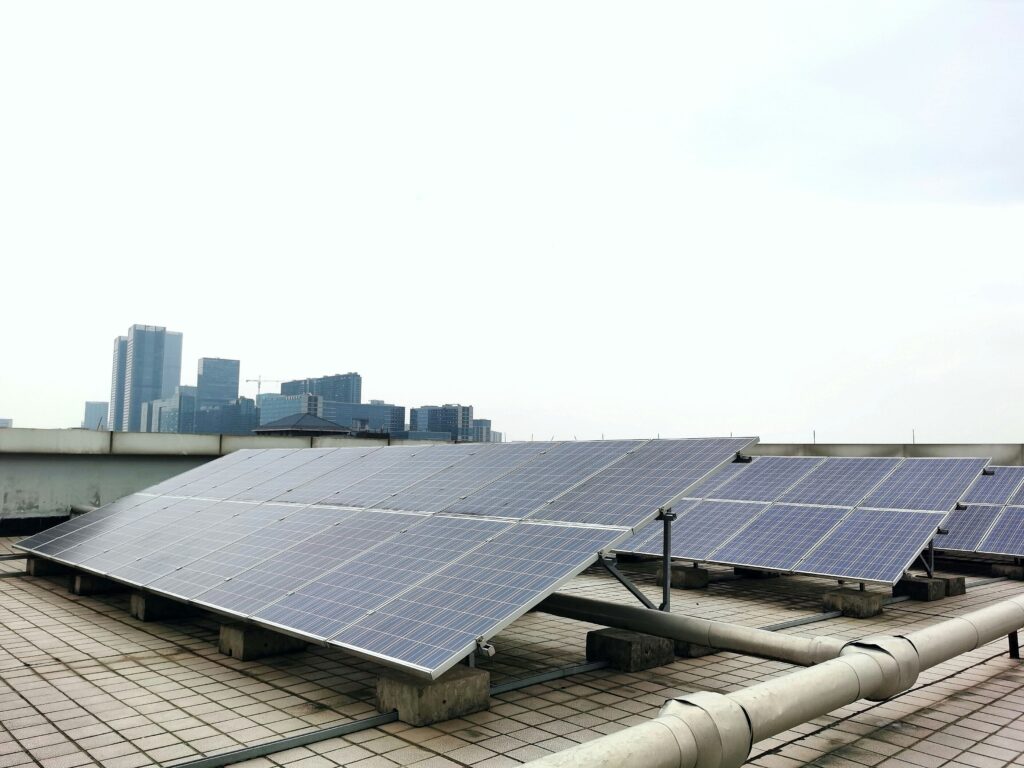 Rooftop solar panel system installed on a commercial building with a city skyline in the background, showcasing sustainable energy solutions offered by solar companies in Kerala for urban properties.
